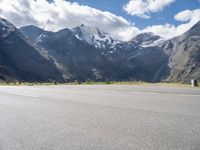 a person is on their cell phone and is running on an asphalt surface with a mountain range in the background