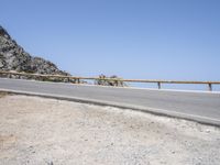 a skateboard is leaning against a metal rail as it rides along the road in front of a mountain