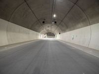 a street is surrounded by a dark tunnel with light from behind it, and only one lane has lanes