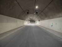 a street is surrounded by a dark tunnel with light from behind it, and only one lane has lanes