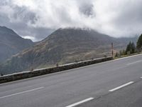 a large mountain in the background with a road running underneath it and people riding on a motorcycle