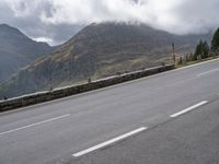 a large mountain in the background with a road running underneath it and people riding on a motorcycle