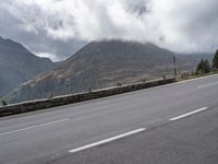 a large mountain in the background with a road running underneath it and people riding on a motorcycle