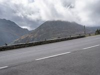 a large mountain in the background with a road running underneath it and people riding on a motorcycle