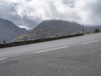 a large mountain in the background with a road running underneath it and people riding on a motorcycle