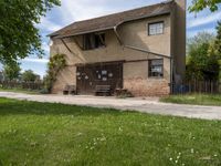 a brick and cement building sitting on the side of a road next to a green grass field