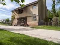 a picnic table sits on the edge of a dirt road outside a building with a fence and a bench underneath it