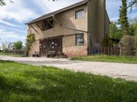 a picnic table sits on the edge of a dirt road outside a building with a fence and a bench underneath it