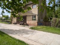 a picnic table sits on the edge of a dirt road outside a building with a fence and a bench underneath it