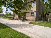 a picnic table sits on the edge of a dirt road outside a building with a fence and a bench underneath it