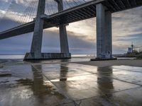 a concrete paved sidewalk with a very large bridge in the background overcast sky and water