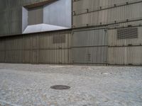 a city fire hydrant in front of a brick sidewalk next to a building, which looks like a metal warehouse