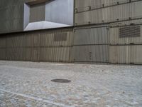 a city fire hydrant in front of a brick sidewalk next to a building, which looks like a metal warehouse