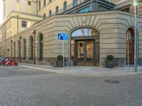 a picture of the entrance to a building in a city street area with two motorcycles in front of the entrance