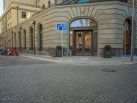 a picture of the entrance to a building in a city street area with two motorcycles in front of the entrance