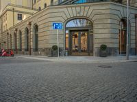 a picture of the entrance to a building in a city street area with two motorcycles in front of the entrance