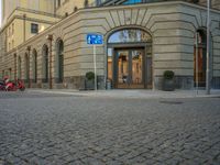 a picture of the entrance to a building in a city street area with two motorcycles in front of the entrance