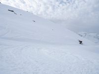 a snowboarder on skis going down a snowy slope in the mountains at high altitude