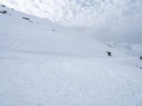 a snowboarder on skis going down a snowy slope in the mountains at high altitude