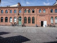 two large buildings on a brick street with bicycles in front of them and a car sitting at the top of them