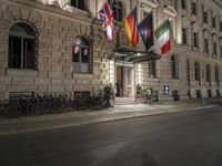 a building with a number of flags flying in it at night in a city street