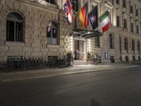 a building with a number of flags flying in it at night in a city street