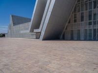 a white building with several steps and large glass panels in the facade is a mosaic that depicts a man