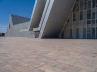 a white building with several steps and large glass panels in the facade is a mosaic that depicts a man