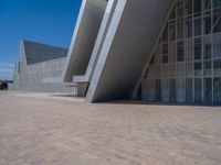 a white building with several steps and large glass panels in the facade is a mosaic that depicts a man