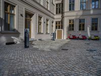 an empty parking lot with plants in the ground and on the side of the building, there is an enclosed area and windows