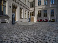 an empty parking lot with plants in the ground and on the side of the building, there is an enclosed area and windows