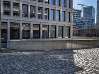 the large office building is located in the center of a cobblestone plaza of the city