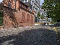 a long empty brick street with tall buildings in the background on a sunny day with some people walking around