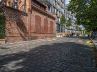 a long empty brick street with tall buildings in the background on a sunny day with some people walking around