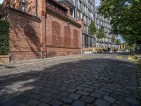 a long empty brick street with tall buildings in the background on a sunny day with some people walking around