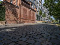 a long empty brick street with tall buildings in the background on a sunny day with some people walking around