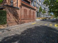 a long empty brick street with tall buildings in the background on a sunny day with some people walking around