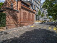 a long empty brick street with tall buildings in the background on a sunny day with some people walking around