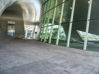 a man on his skateboard in front of a glass building with a curved entry