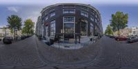 a panorama camera lens is of a store front in a city setting and a parking lot