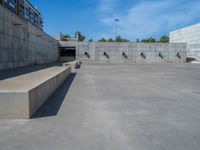 the empty parking lot in front of a wall with apartment buildings on it and a skateboarder on a ramp