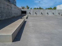 the empty parking lot in front of a wall with apartment buildings on it and a skateboarder on a ramp