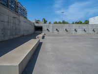 the empty parking lot in front of a wall with apartment buildings on it and a skateboarder on a ramp