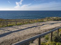 a wooden walkway over looking the ocean on a clear day in the sun near a path