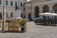 wooden boxes with plants on each side sit on the gravel ground outside a building and a parking meter is in the foreground