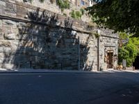 the shadow from a stone wall is cast onto the street by it as it passes through a building