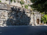 the shadow from a stone wall is cast onto the street by it as it passes through a building