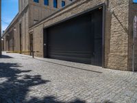 two windows in the side of a brick building, with a black garage door and brown door