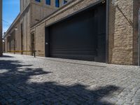 two windows in the side of a brick building, with a black garage door and brown door