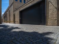 two windows in the side of a brick building, with a black garage door and brown door